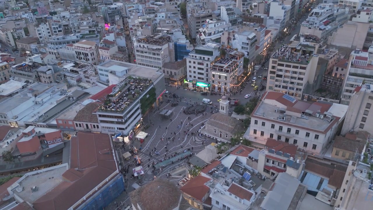 Vista aerea dall'alto della vivace Piazza Monastiraki ad Atene al tramonto con le luci della città.