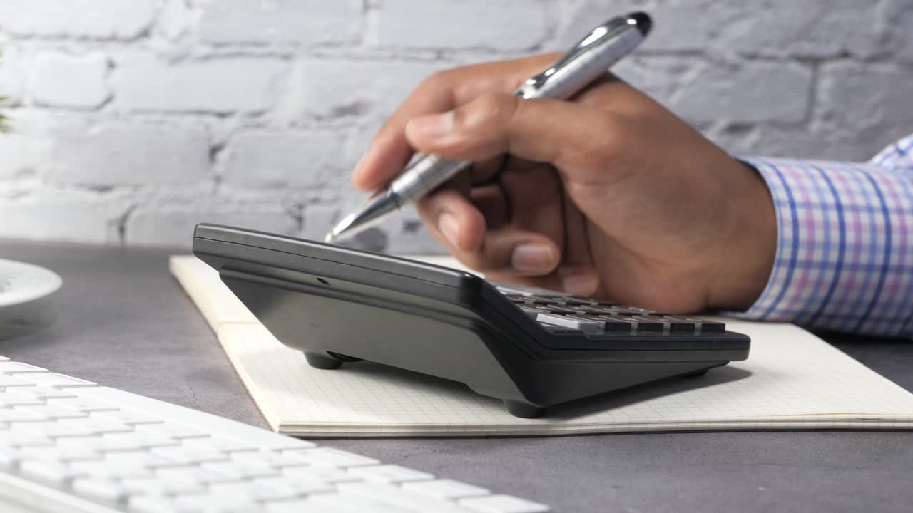 persona que utiliza una calculadora y un bolígrafo