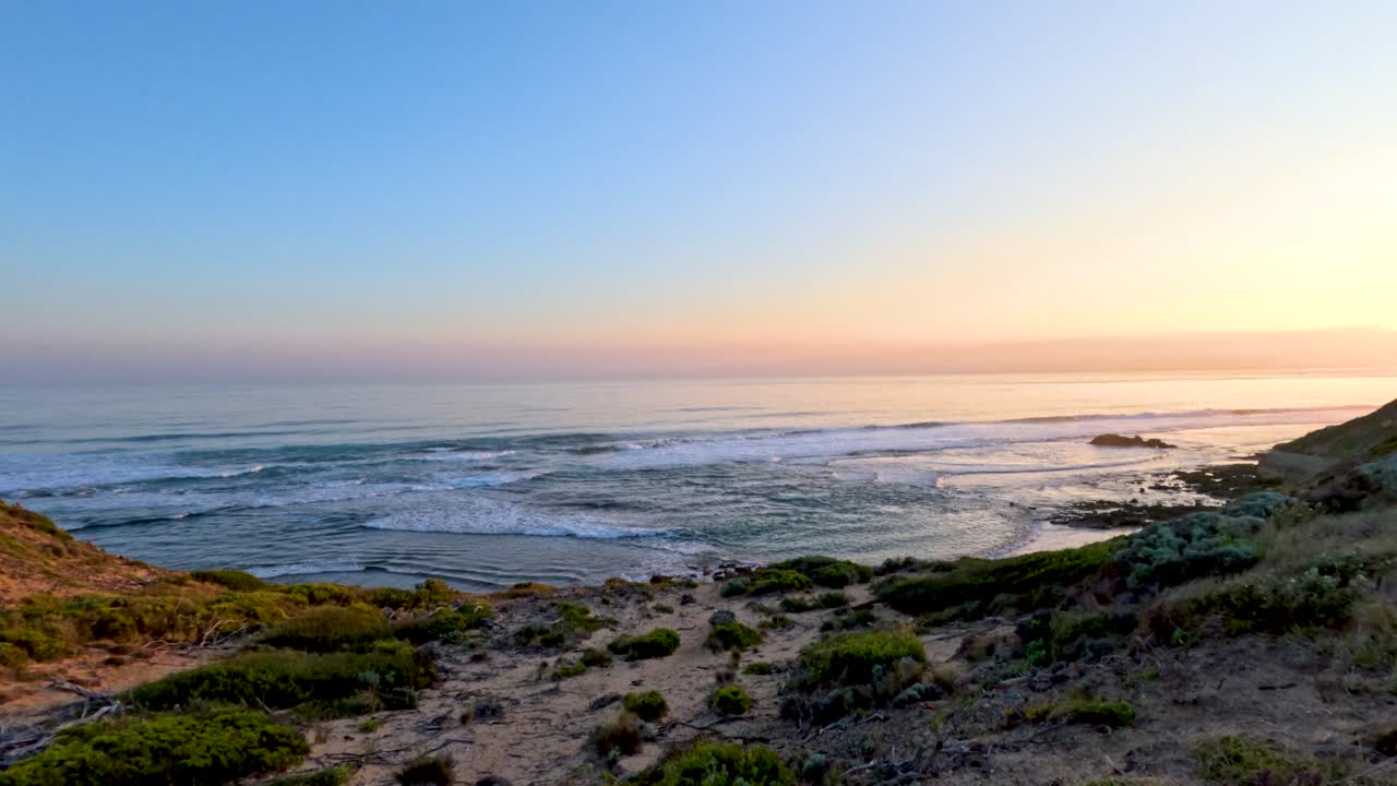 A serene sunset view over coastal cliffs and ocean waves, captured with smooth camera movement and warm lighting