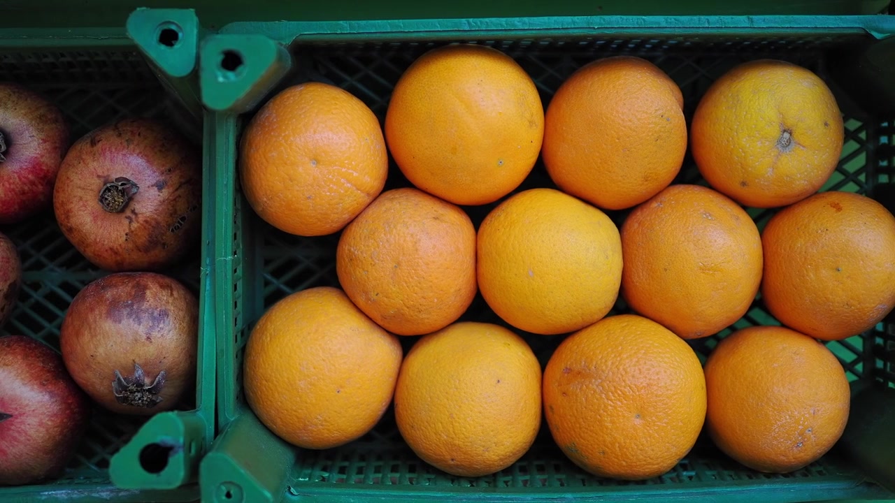Top View of Fresh Oranges and Pomegranates in Green Plastic Crates