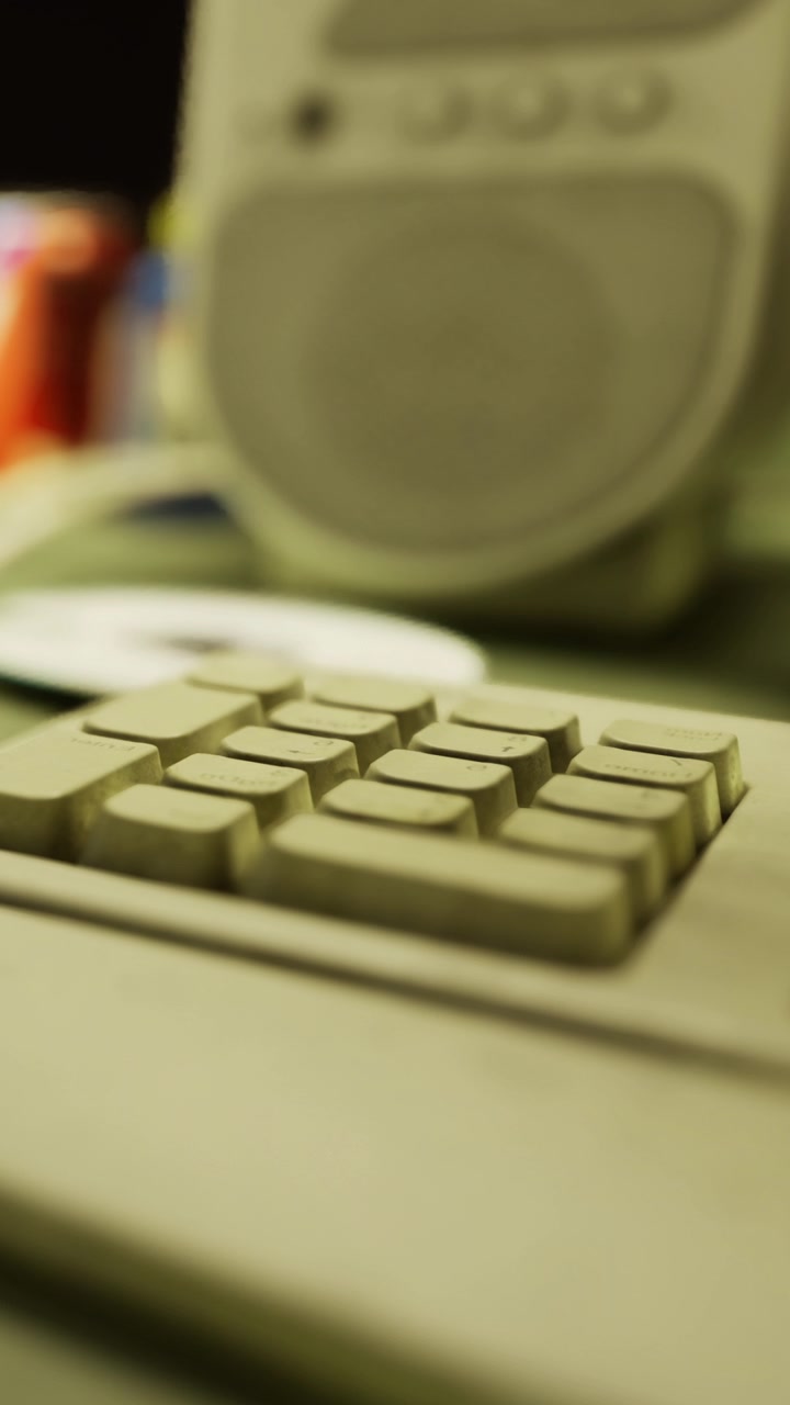 Old computer keyboard and speaker on a desk in a busy workspace