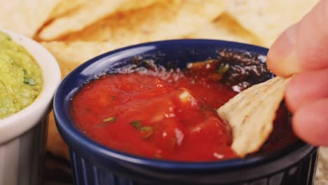 dipping tortilla chips in salsa with guacamole