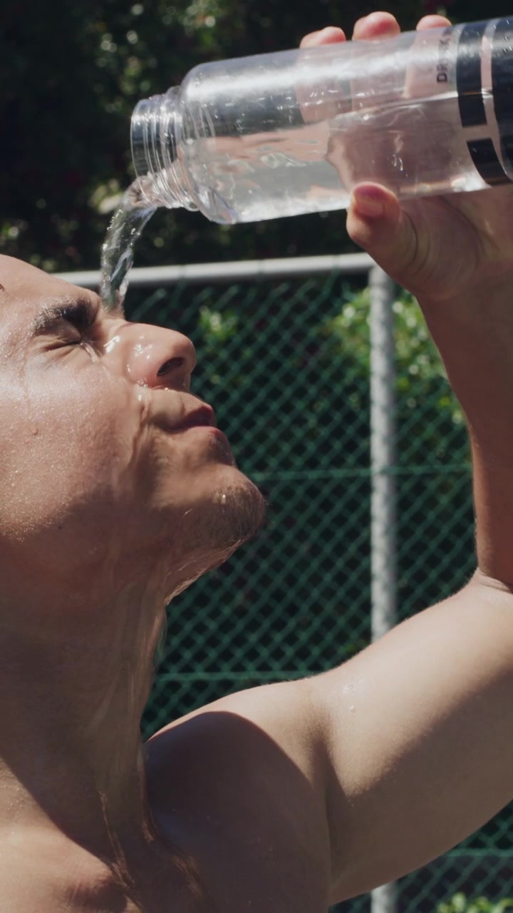 Athletic Man Pouring Water Over His Face to Cool Down