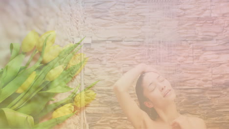 animation of yellow flowers over happy biracial woman washing in shower