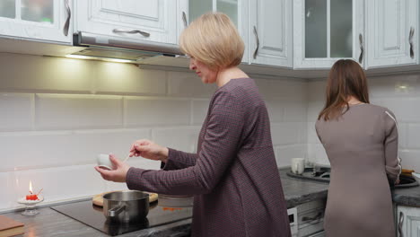 madre e hija cocinando juntos en una cocina moderna y bien iluminada, preparando la cena con ingredientes y utensilios, creando una cálida atmósfera familiar