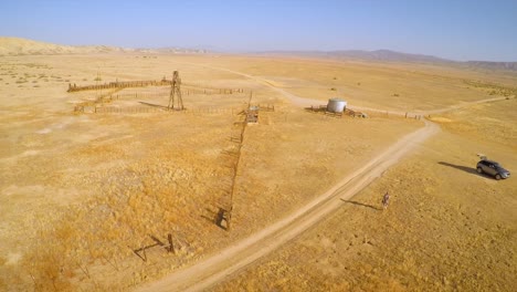 an aerial over a man walking to his car near an abandoned ranch in the desert of the carrizo plain