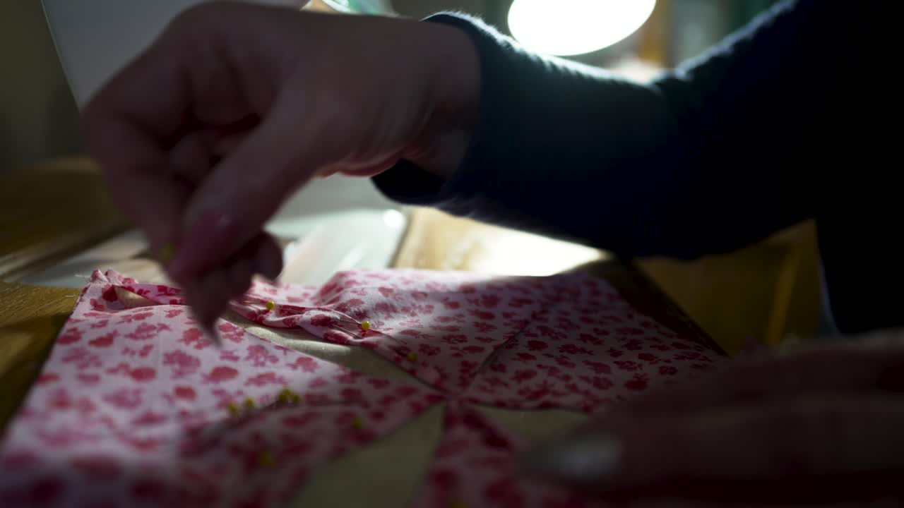 Crafty homemaker pinning quilt block together before sewing the pieces in place - isolated close up