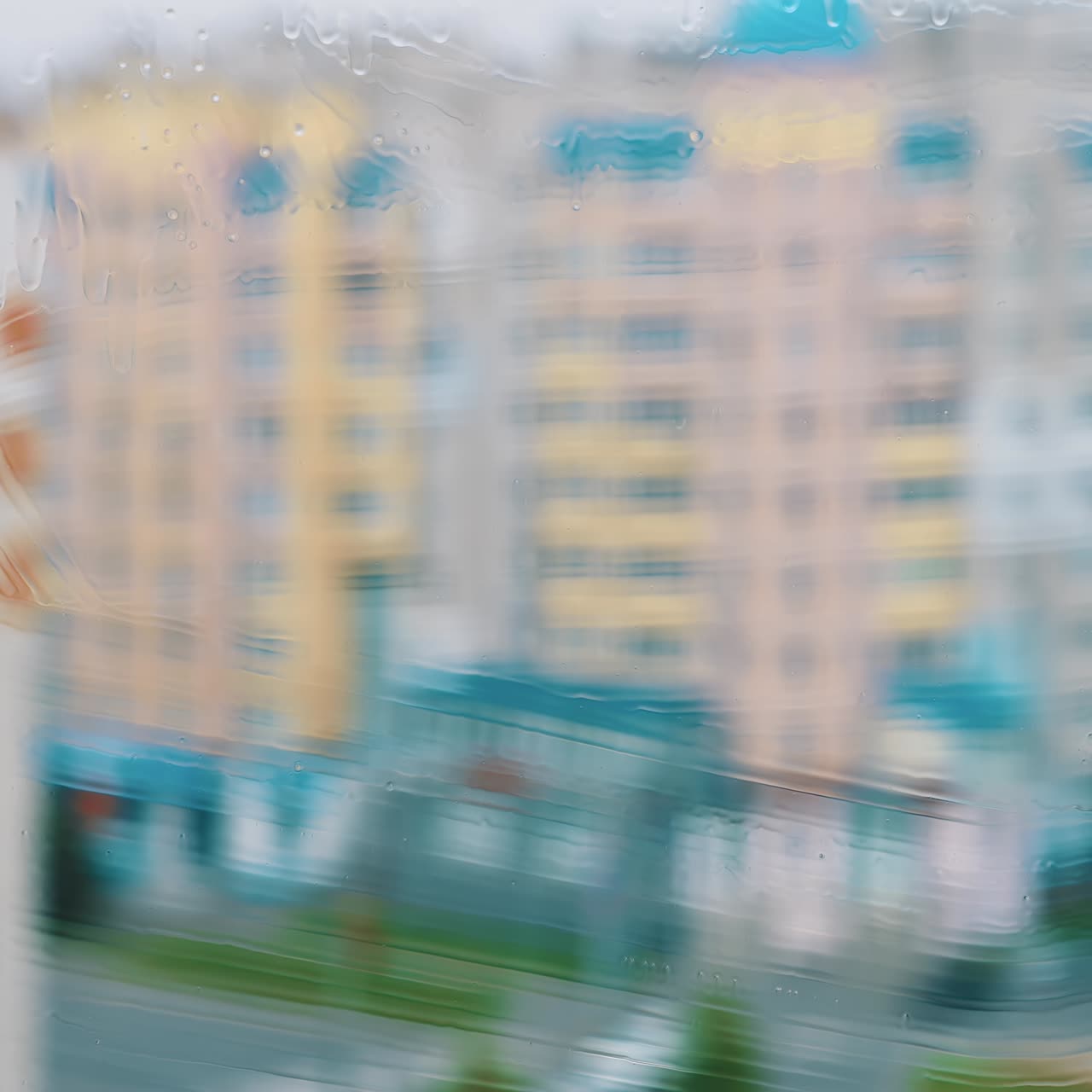 Cleaning dirty window with solution. Worker using household brush to wash window with special liquid inside. Blurred multi-storey building backdrop
