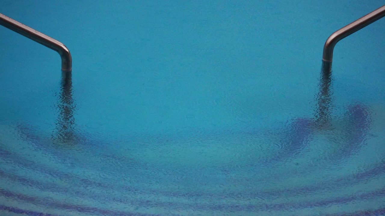Superfície da água da piscina devido à queda de gotas de água. Ondas radiais de chuva na água.
