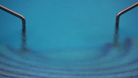 pool water surface due to falling drops of water. radial waves of a rain on the water.