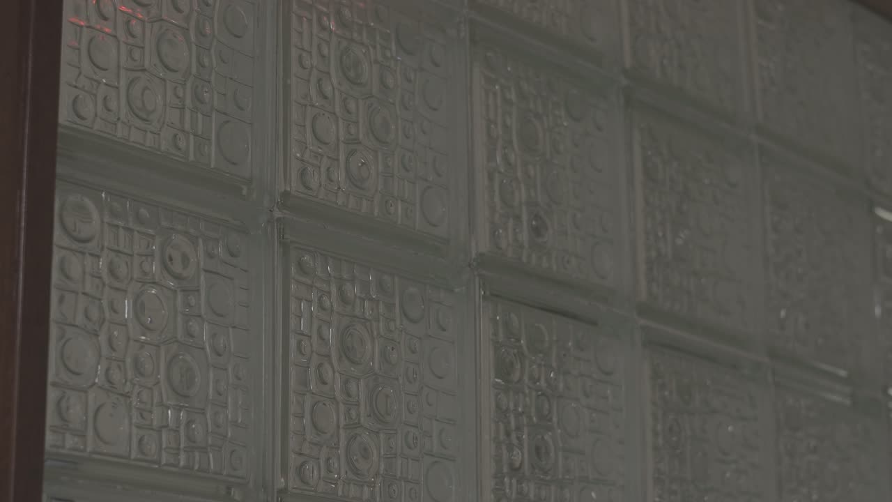 Static shot of a rain-streaked window with blurred police lights flashing in the background — tense urban atmosphere for crime dramas