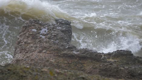 big waves hitting the abandoned concrete coast defense building ruins in stormy weather