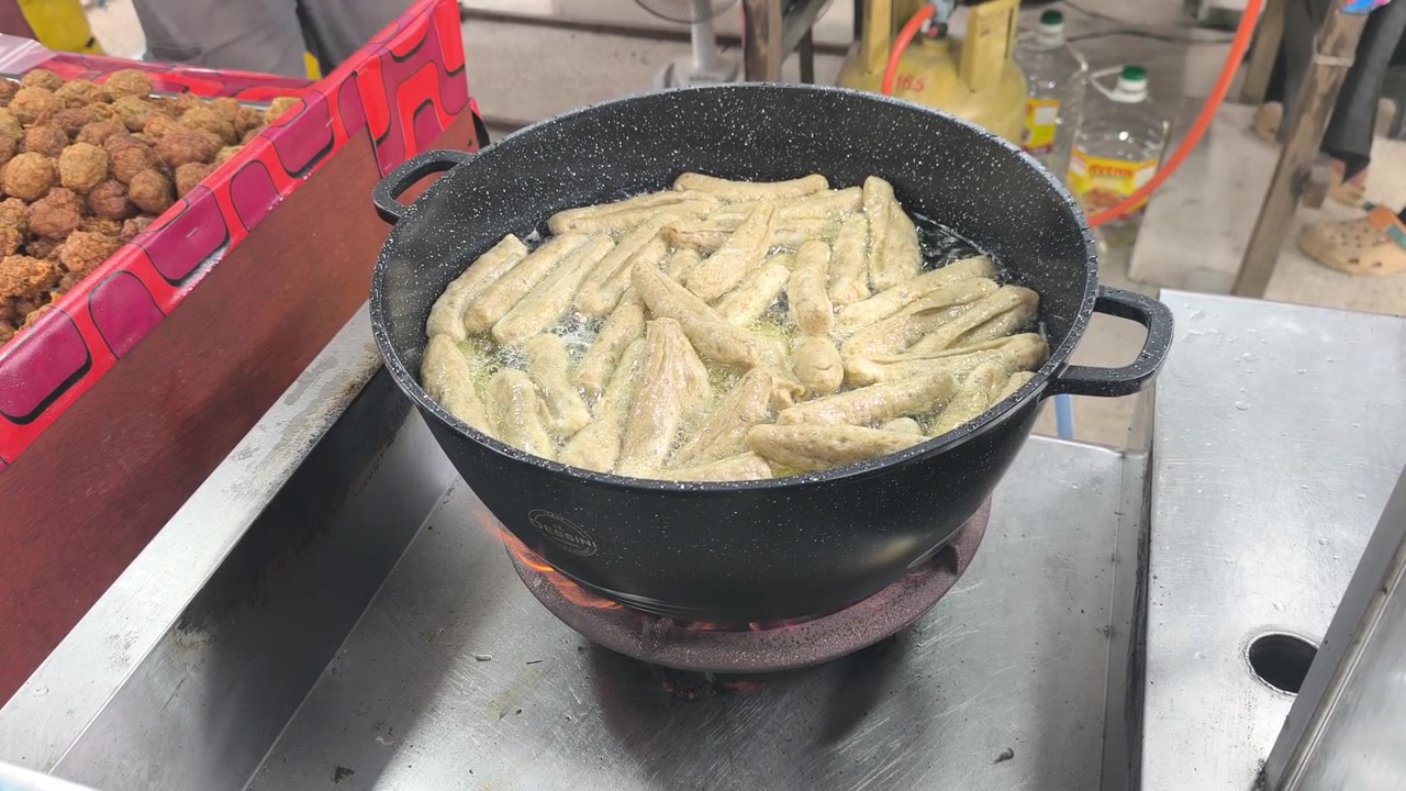 Sizzling keropok lekor being deep-fried to perfection in hot oil. This traditional Malaysian fish cracker snack from Terengganu is made from a flavorful blend of fish paste and flour.