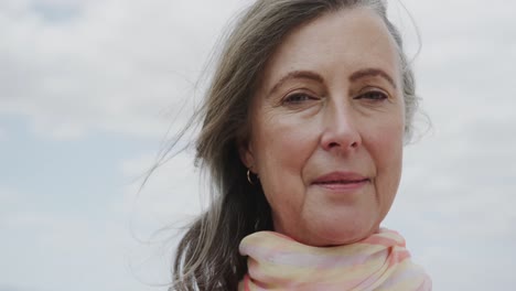 Portrait-of-happy-senior-caucasian-woman-smiling-against-cloudy-sky,-in-slow-motion