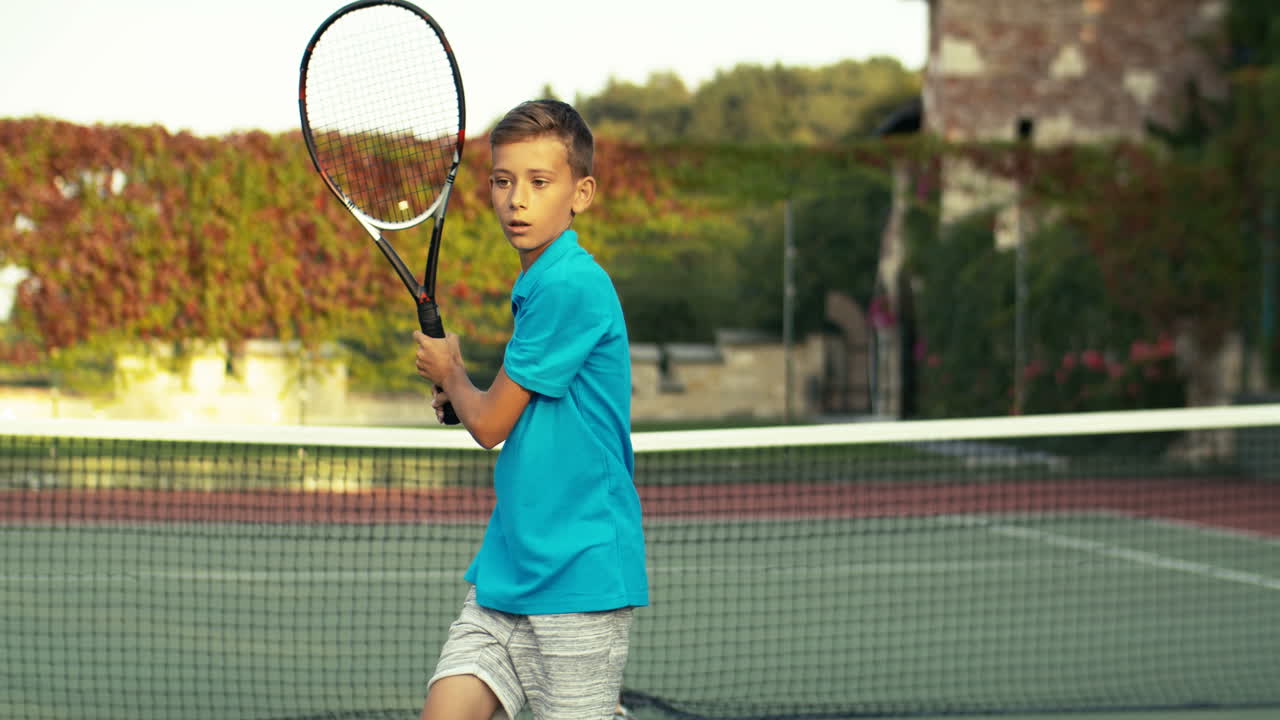 Teen Boy With Racket Training On Outdoor Tennis Court On A Summer Day