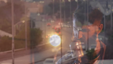 male singer singing into retro mic in recording studio, showing layered city street reflections