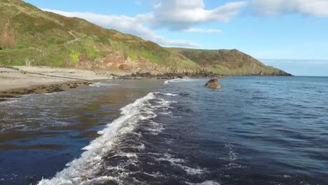 Vista-Aérea-De-Las-Olas-Rompiendo-En-La-Playa-Rocosa-Con-Acantilados-De-Fondo-En-Porth-Ysgo-En-La-Península-De-Llyn-En-Gales