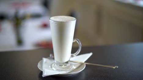 preparing coffee latte in a coffeehouse, starting to pour the coffee in