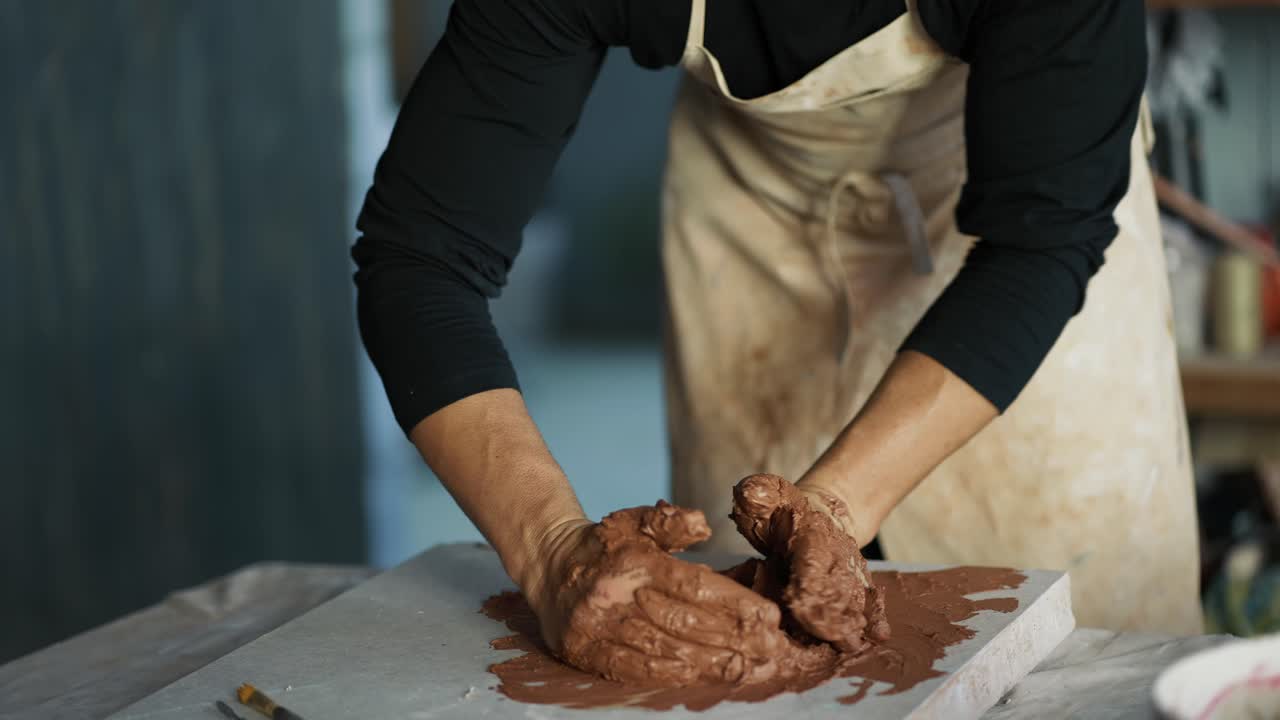 A male potter kneads brown clay on a special board. Professional everyday life