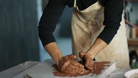 a male potter kneads brown clay on a special board. professional everyday life