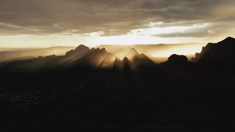 sunburst over silhouetted mountains in sedona, arizona during sunrise