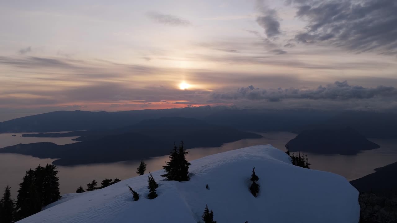 Snowy mountain top at sunset overlooking islands and ocean in BC, Canada.