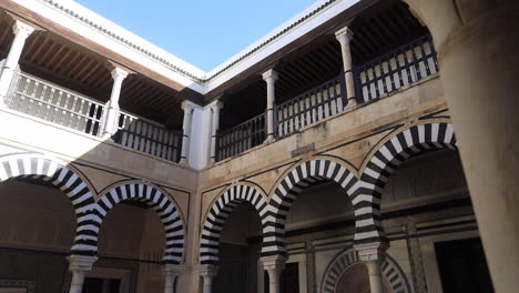 traditional tunisian courtyard with intricate arches and striped patterns under a bright blue sky