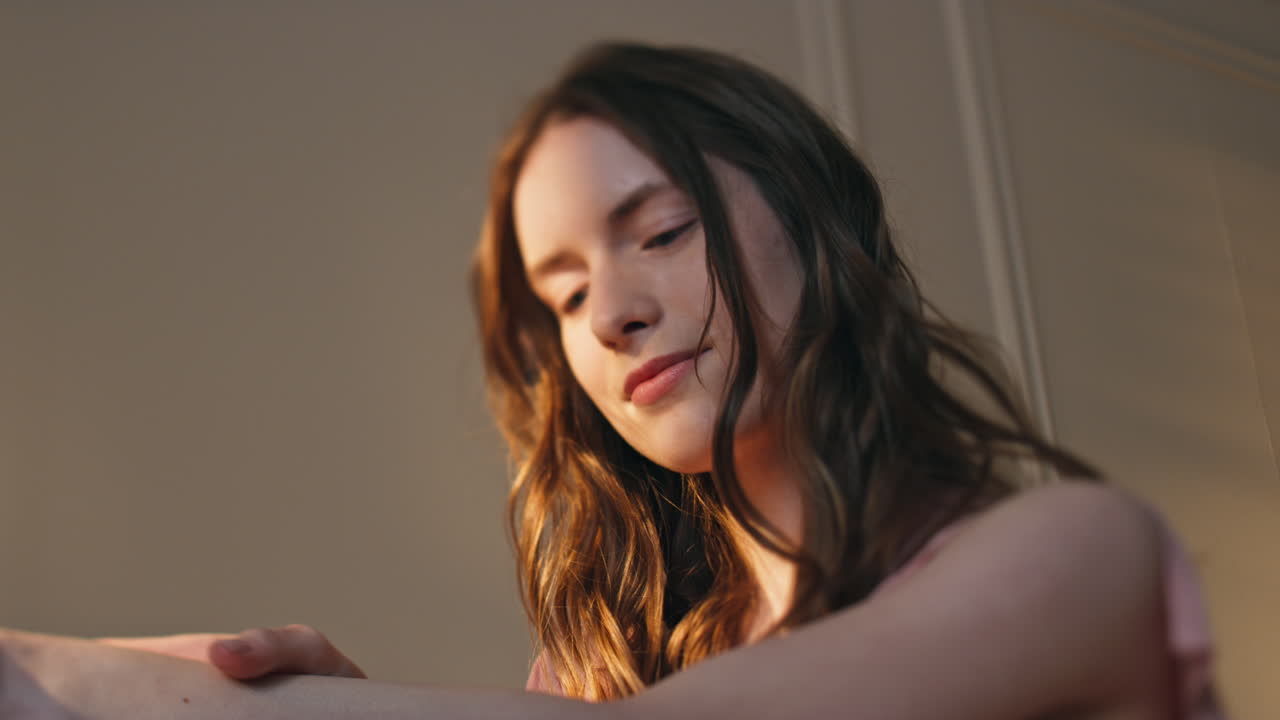 빛 아래 부드러운 피부에 로션을 적용하는 클로즈업 소녀. 평온한 여자가 즐기고 있습니다.