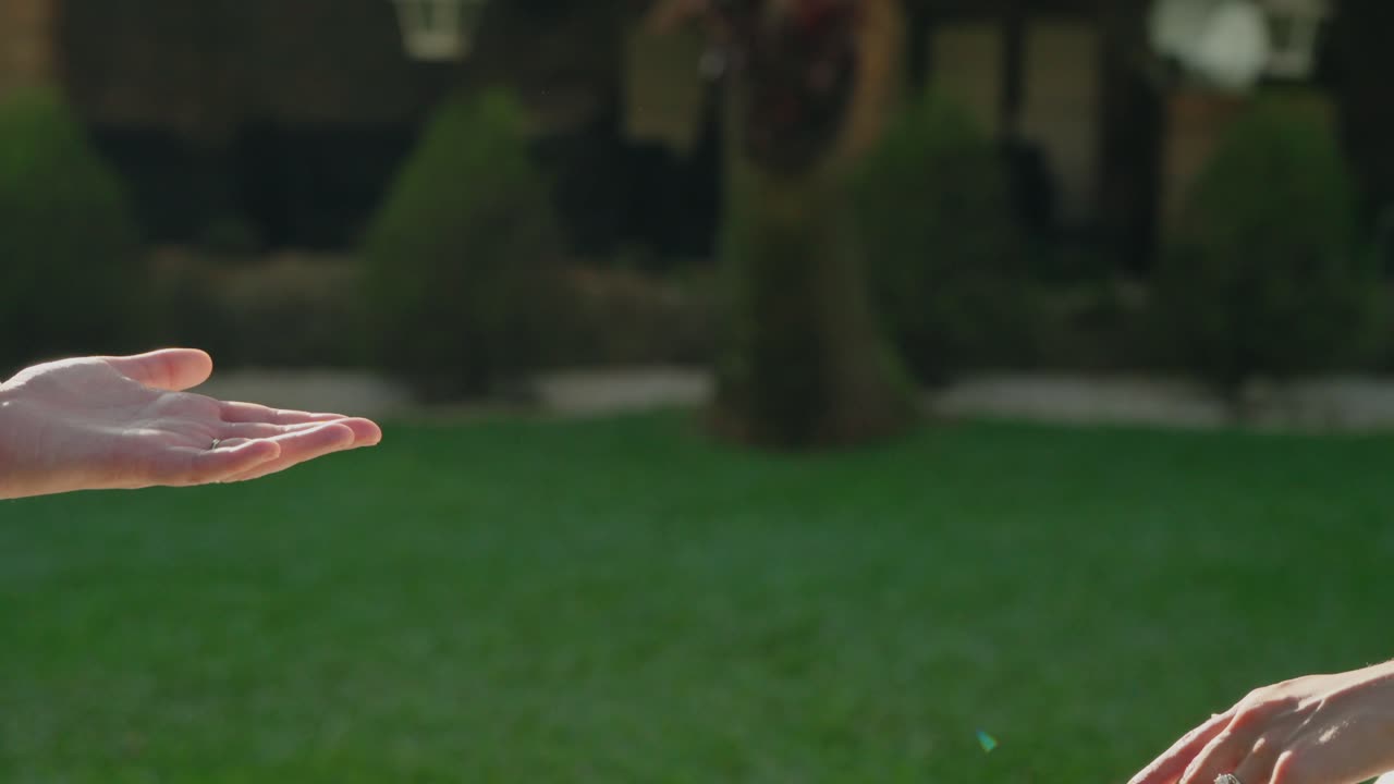 Bride and groom gently extending hands toward each other in an outdoor setting