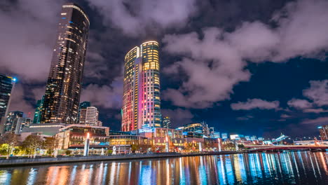 Melbourne-Australia-Victoria-Ciudad-Mirando-Sobre-El-Río-Yarra-Y-Casino-Con-Llamas-Y-Reflejos-De-Agua-Timelapse-Noche-En-La-Ciudad-Nubes-Colores-Vivos-Banco-Sur