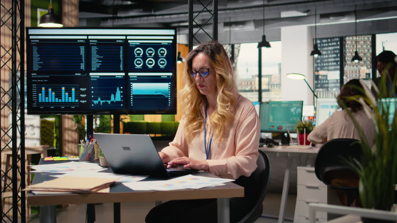 Vertical Video Businesswoman at her desk on analytics displayed with her laptop