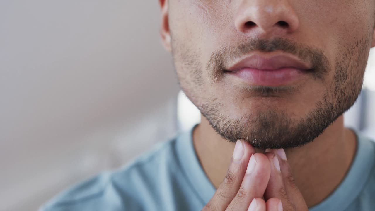 primer plano de un feliz hombre biracial examinando su cara y barba en el baño y sonriendo, cámara lenta