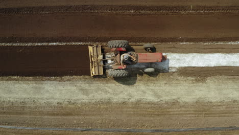Tractor-Rojo-Arando-El-Campo-Y-Surcando-En-Una-Plantación,-Concepto-Agronómico,-Disparo-De-Drones-En-Ascenso-Cenital