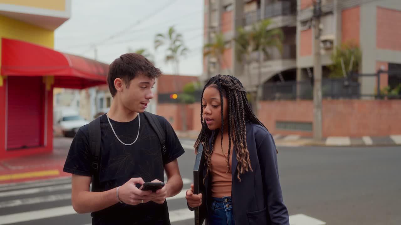 Two Teenagers Chatting and Using a Smartphone on a City Street