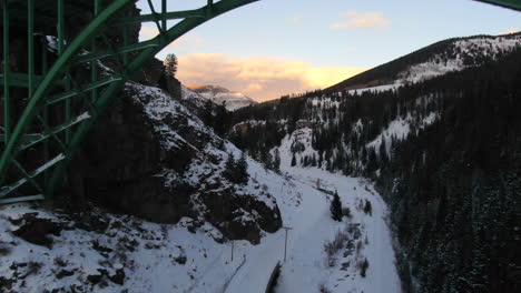 Drone-Cinematográfico-Aéreo-Vail-Avon-Acantilado-Rojo-Icónico-Colorado-Debajo-Del-Puente-Mediados-De-Invierno-En-La-Nieve-Atardecer-Tardío-Movimiento-Hacia-Atrás