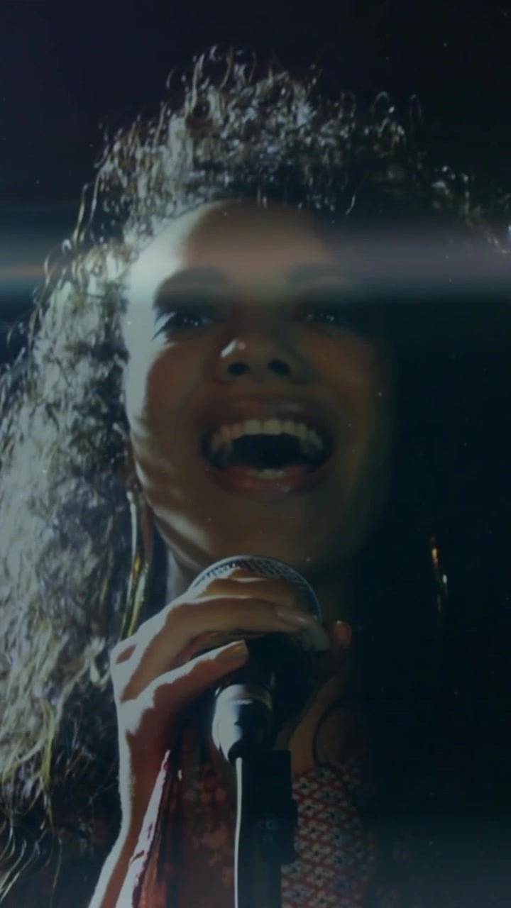 Vertical video: Woman singer starting song gripping mic tilting and tossing hair amid stage flares