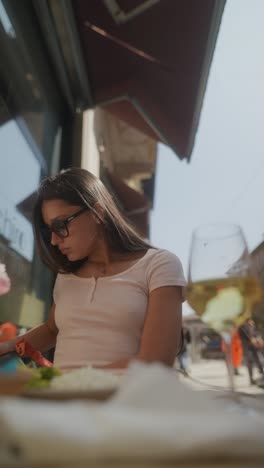 woman enjoying a meal and wine at an outdoor cafe