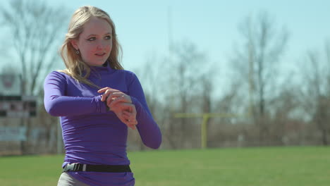 teen girl runner checks her time on her watch after a run in her cool down walk after a run on the track