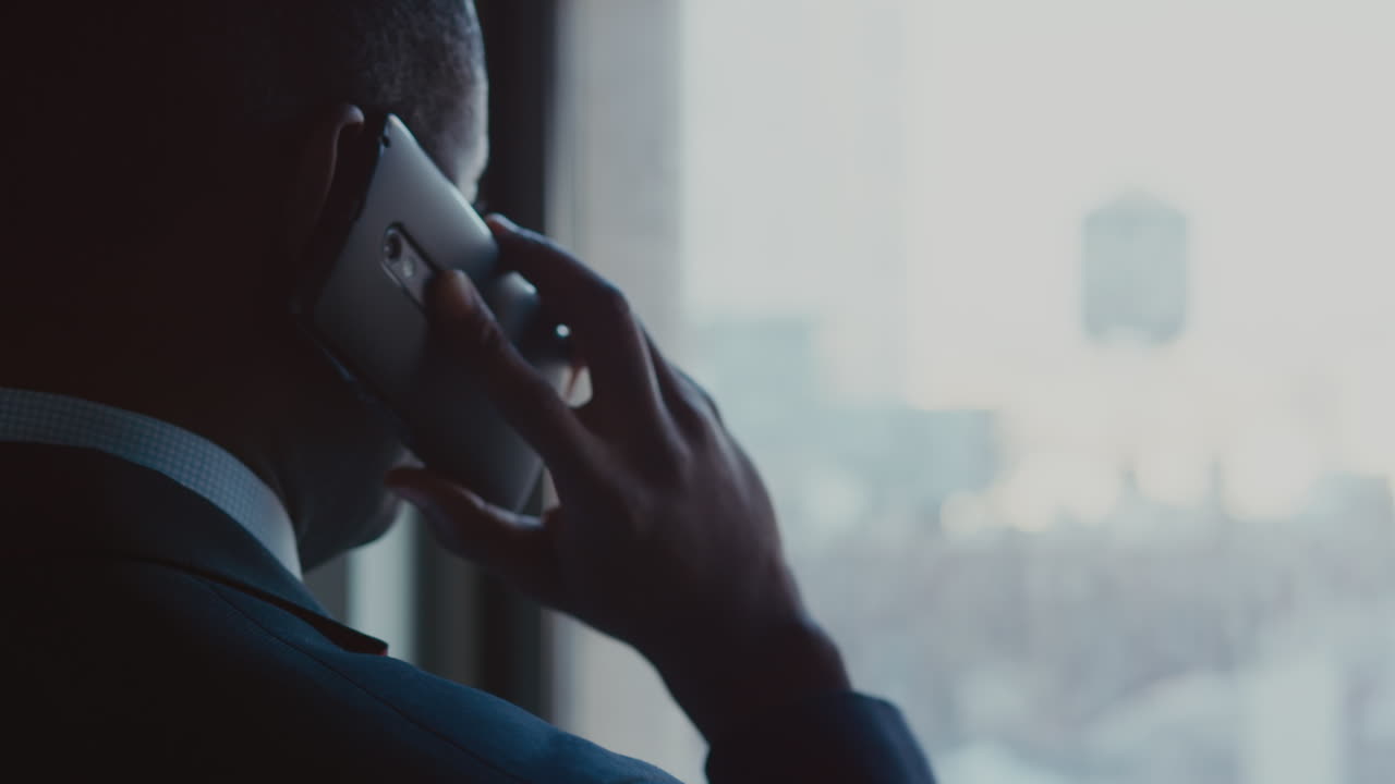 A businessman talks on a phone while looking out a window