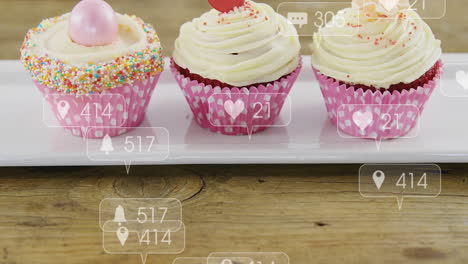 cupcakes with social media notification animation over wooden background