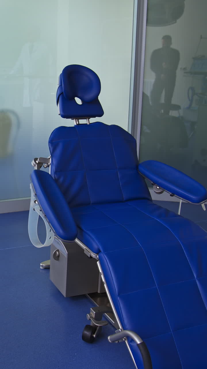 Blue comfortable folding chair in dentist's cabinet. Light room with diverse equipment for stomatological purposes. Vertical video