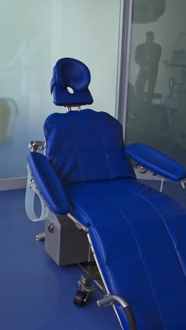 blue comfortable folding chair in dentist's cabinet. light room with diverse equipment for stomatological purposes. vertical video