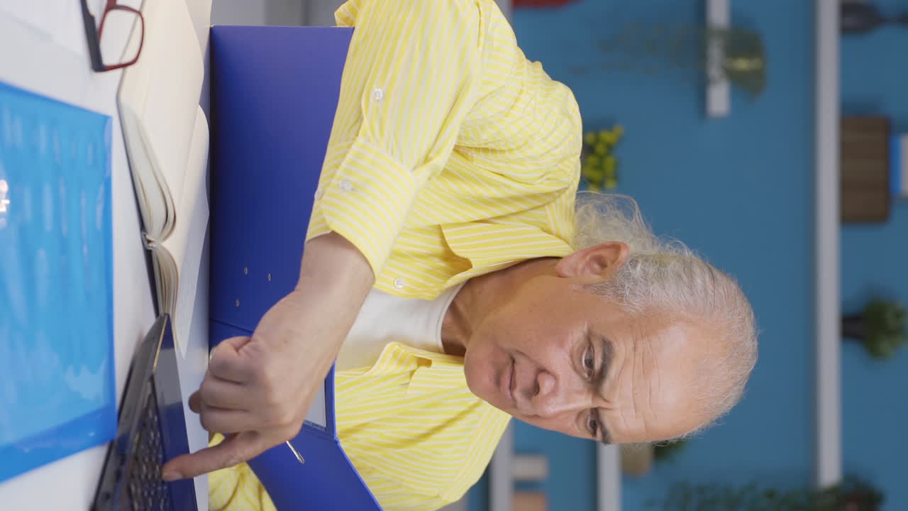 홈 오피스 직원 노인이 서류 파일을 검토하는 수직 비디오.