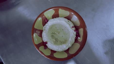 agregando tomate, comino, menta y vertiendo aceite orgánico sobre un plato de berenjena hummus