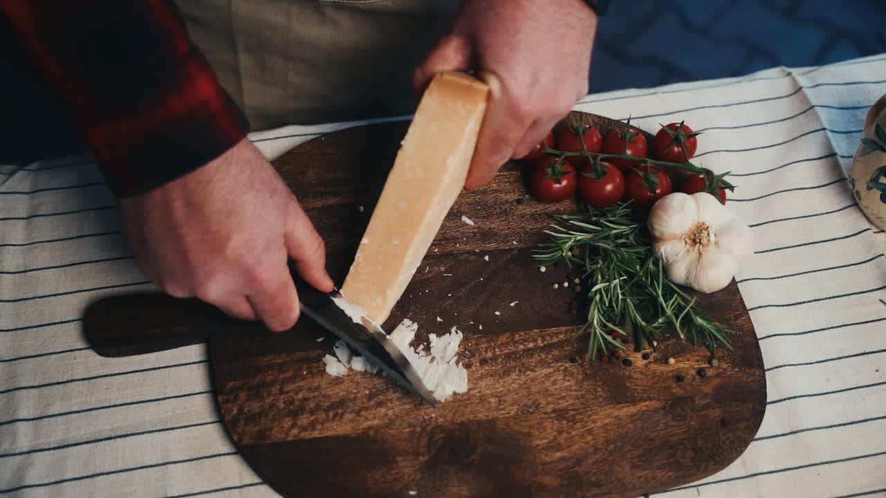River parmesanost på et træbræt med tomater, hvidløg og rosmarin i nærheden