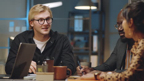 businessman speaking with multiethnic coworkers on night office meeting