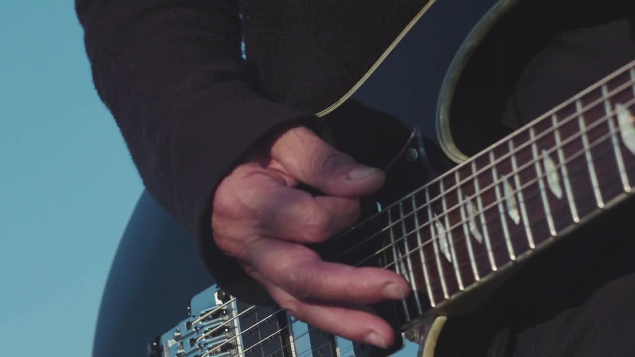primer plano de una persona tocando una guitarra eléctrica