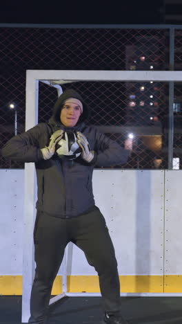 portero enérgico que muestra agilidad y habilidades mientras baila y atrapa una pelota de fútbol durante una intensa sesión de práctica bajo las vibrantes luces nocturnas de la ciudad en un campo deportivo urbano al aire libre