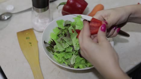 Female-hands-cut-a-sweet-red-bell-Pepper-to-a-salad