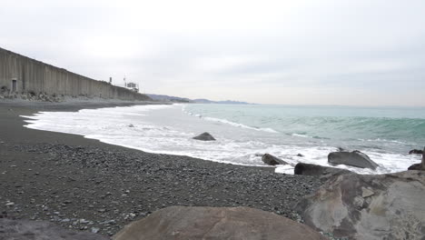 Waves-hitting-the-shore-of-Miyuki-Beach-in-Odawa,-Kanagawa,-Japan-on-a-cloudy-day